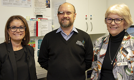 Staff members smiling at the camera. Man in the middle wearing Google Glasses.