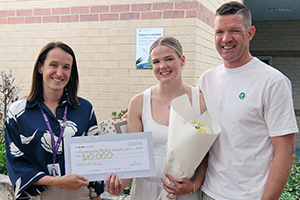 Eilidh Milne stands between her ftaher Alastiar and a woman who is holding an oversized cheque for $10,000