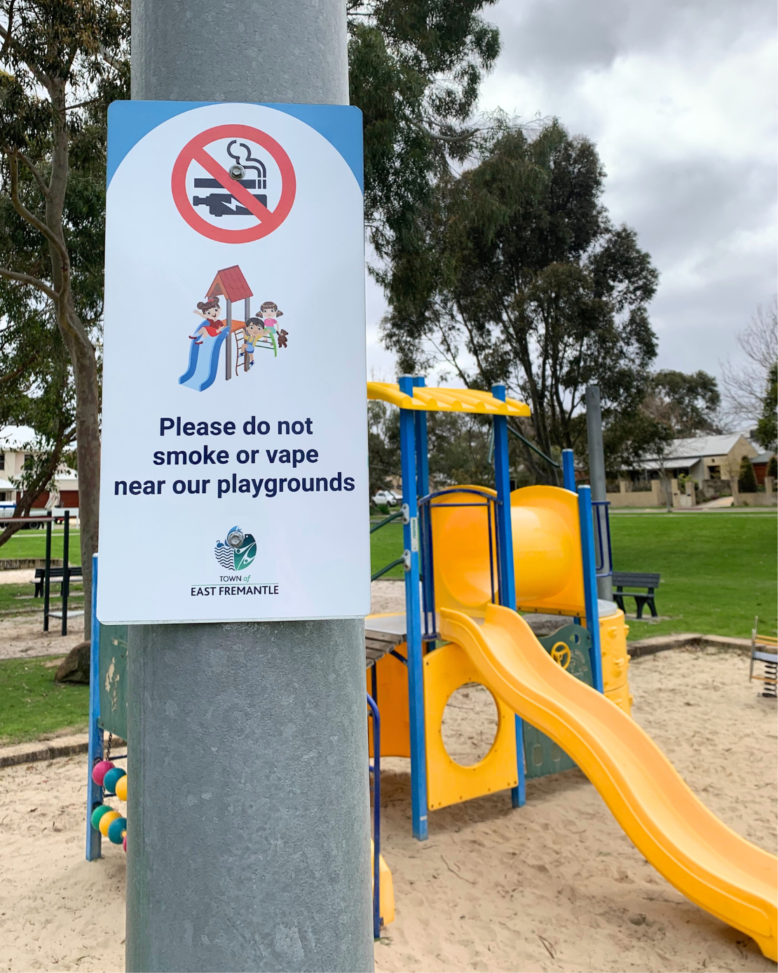 Image of new smoke and vape free signage, with playground in background.