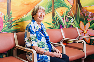 Rae Endersby sits in front of a colourful mural