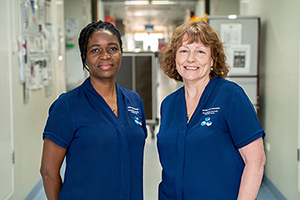 Two nurses stand inside a hospital corridor