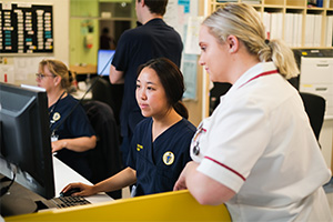 Three female nurses in Fremantle Hospital uniforms look at computer screens