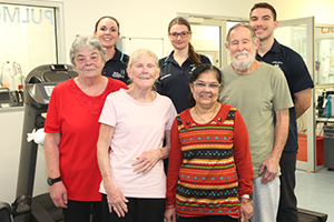 Four pulmonary rehabilitation patients and three FSH staff standing together in the gym smiling