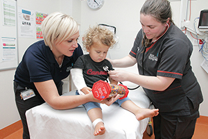 Two female nurses assess a young child
