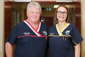 A male clinical nurse specialist and a female nurse unit manager stand beside each other in a doorway