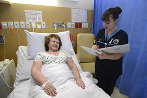 A female nurse talks to a female patient in her bed