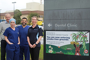 Two male and two female RkPG staff members stand beside a sign reading ‘Welcome to Rockingham General Hospital. You are now entering smoke free grounds’.