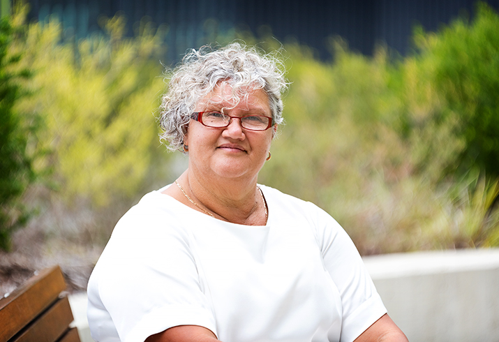 An Aboriginal person sitting in a garden.