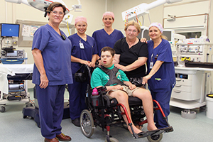 Theatre nursing staff stand by a young man with disability in a wheelchair.