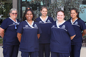Five Aboriginal health practitioners stand together in a garden setting