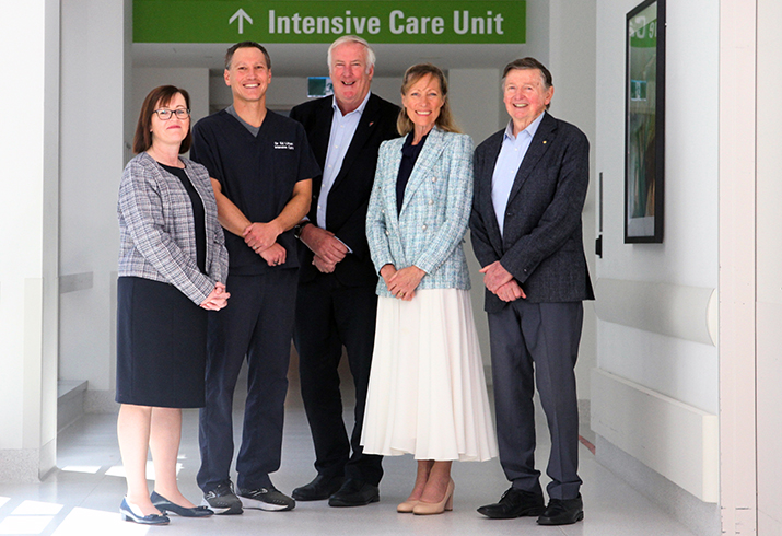 Five people stand together in a hospital hallway. A sign above them reads Intensive Care Unit